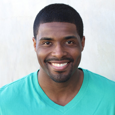 The image shows an elderly couple embracing each other with smiles on their faces, posing for a photograph outdoors during the daytime.