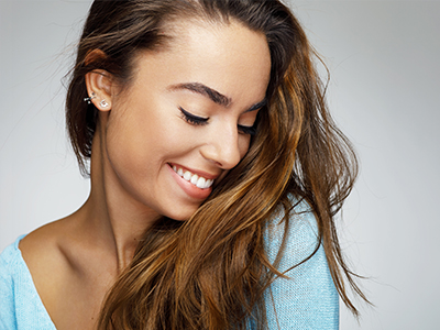 A smiling woman with long hair poses against a light background.