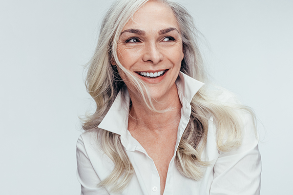 A woman with blonde hair and a smile, wearing a white shirt and leaning slightly towards the camera.