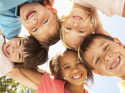 A group of children smiling at the camera, posing together outdoors.